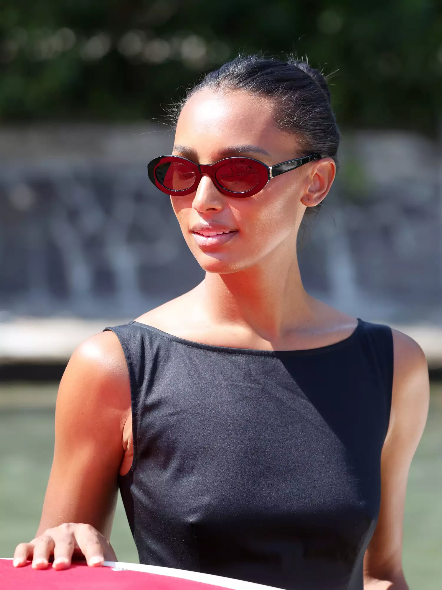 Jasmine Tookes wearing red and black oval shaped sunglasses