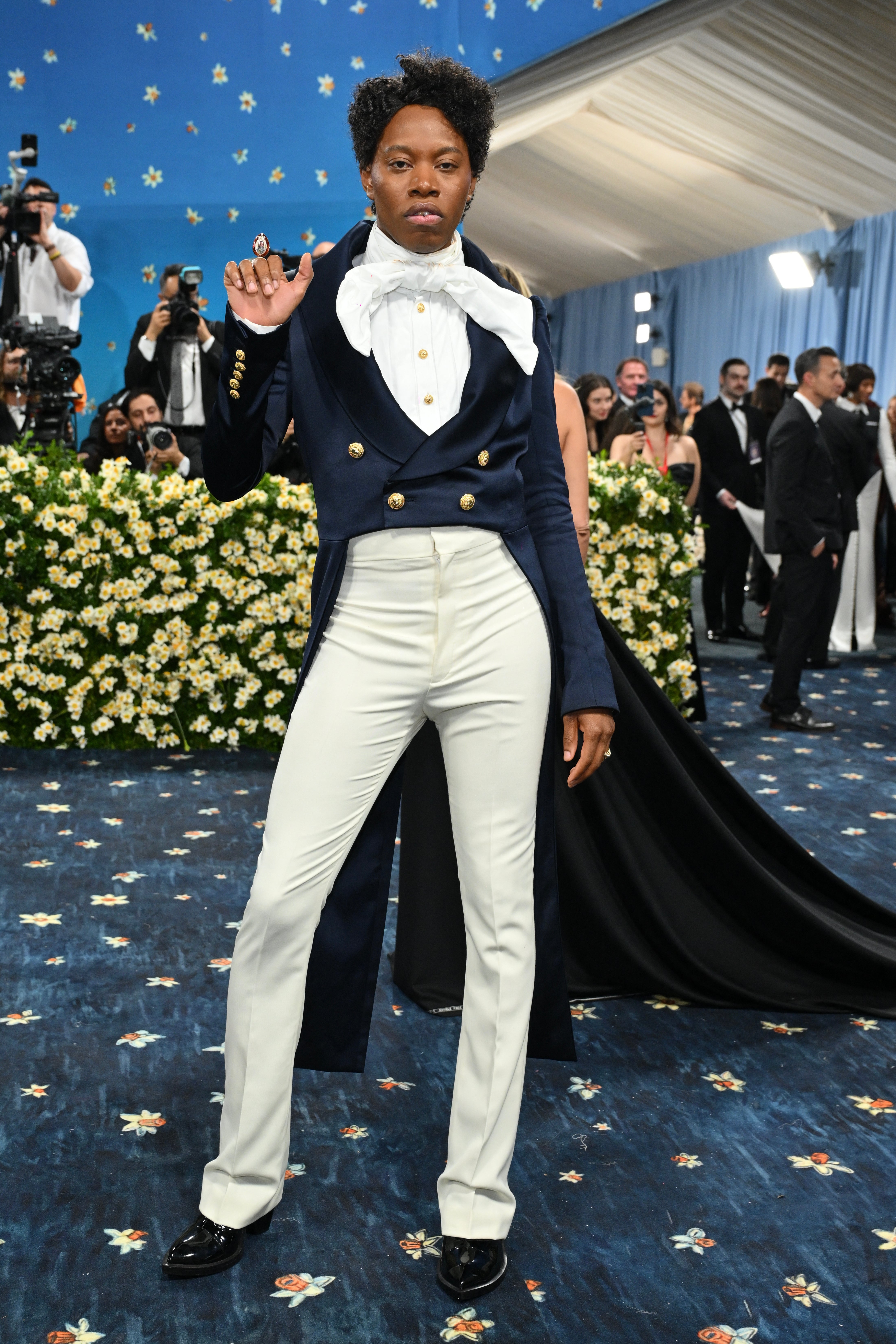 Playwright Jeremy O. Harris wore a cropped navy blue blazer with gold buttons. The blazer was complemented with beige pants and a white shirt with a bow