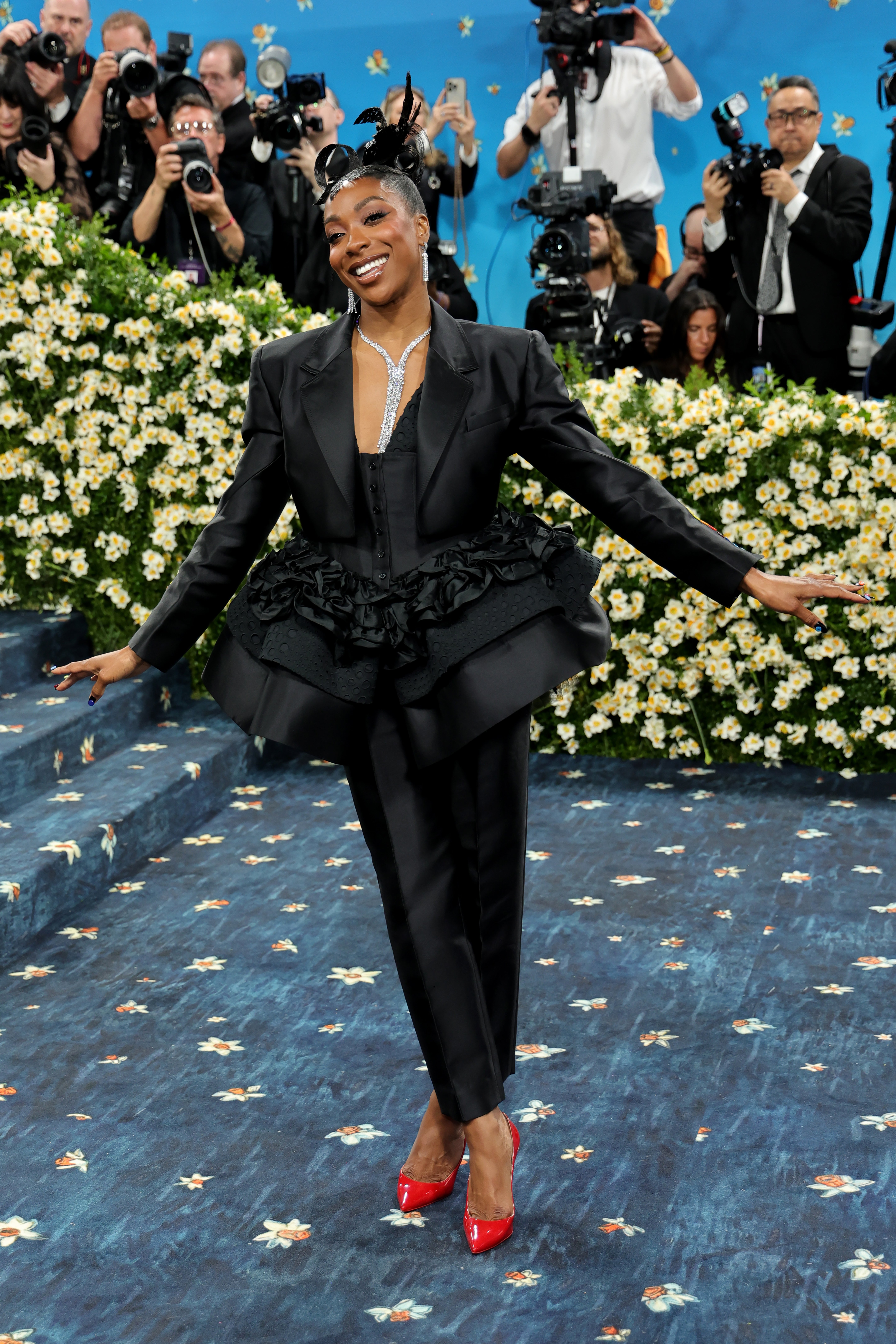 Ego Nwodim wore a classic black suit with a ruffled skirt and matching pants. She added a long diamond necklace and diamond earrings, paired with red heels and a feathered back bow in her hair