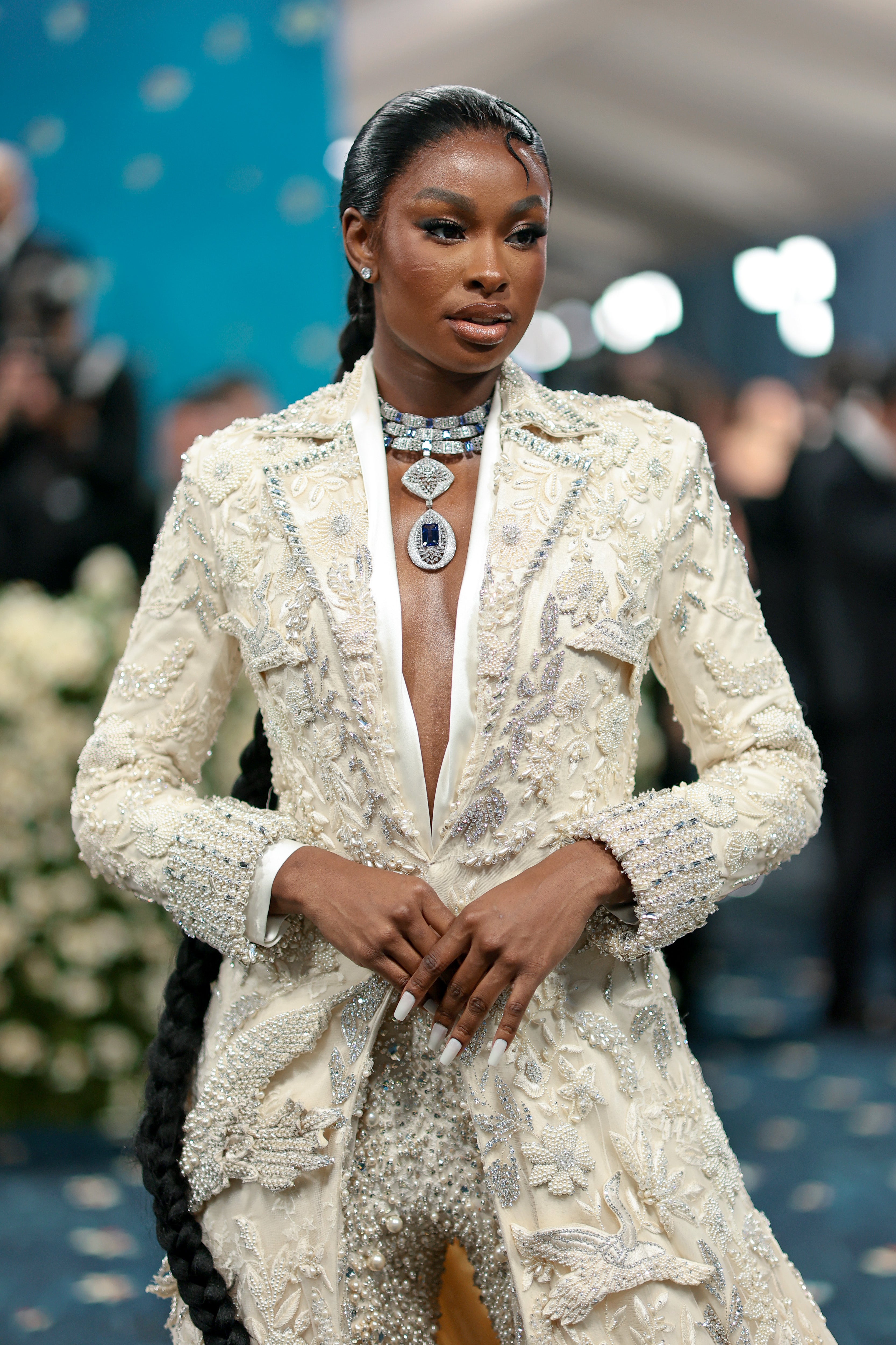 Coco Jones arrived in a cream, floor-length jacket featuring silver embroideries. She wore matching pants adorned with jewels and a silver statement necklace