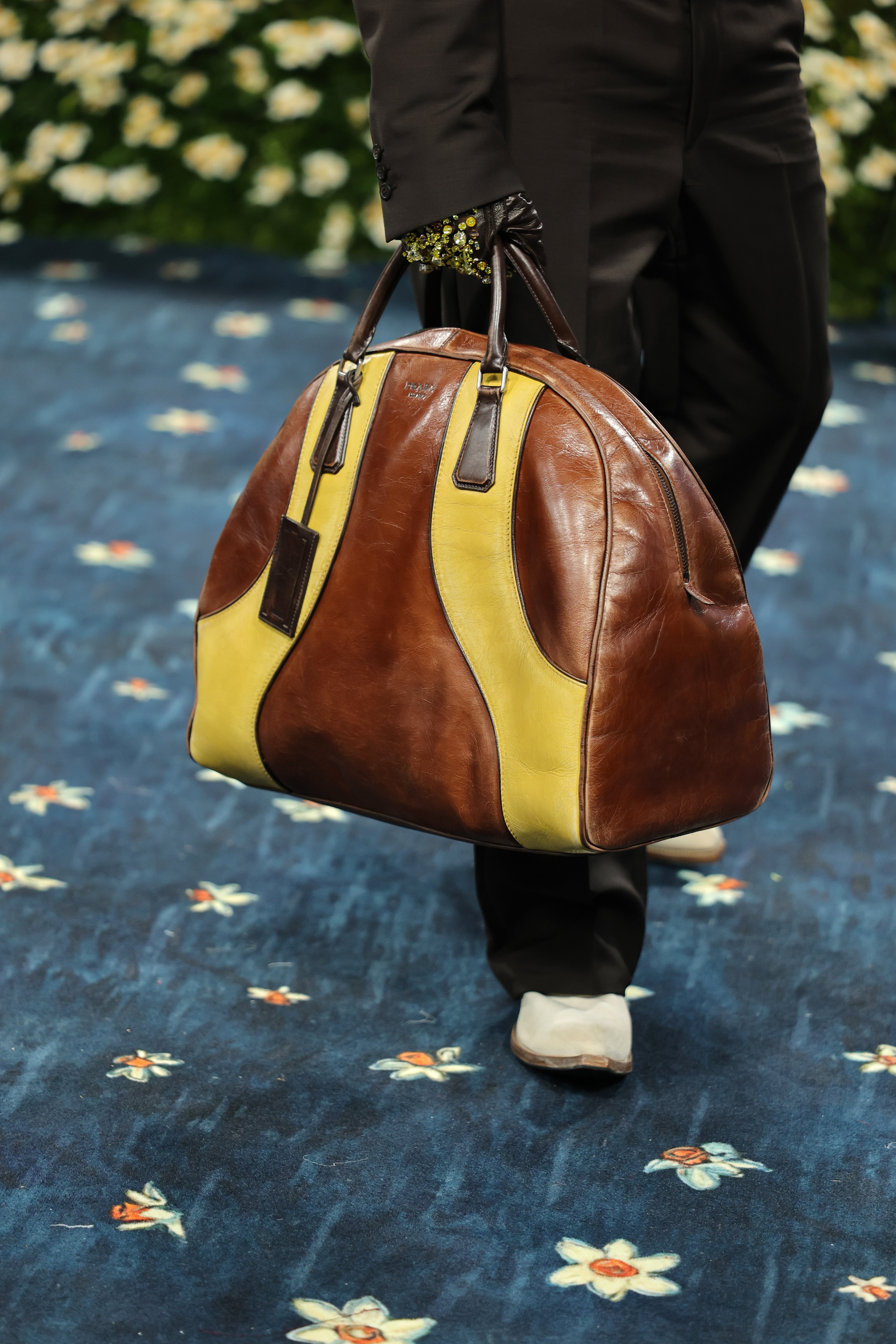 Bad Bunny also wore a pair of brown leather gloves, adorned with yellow jewels, and had a yellow and brown Prada bag in hand