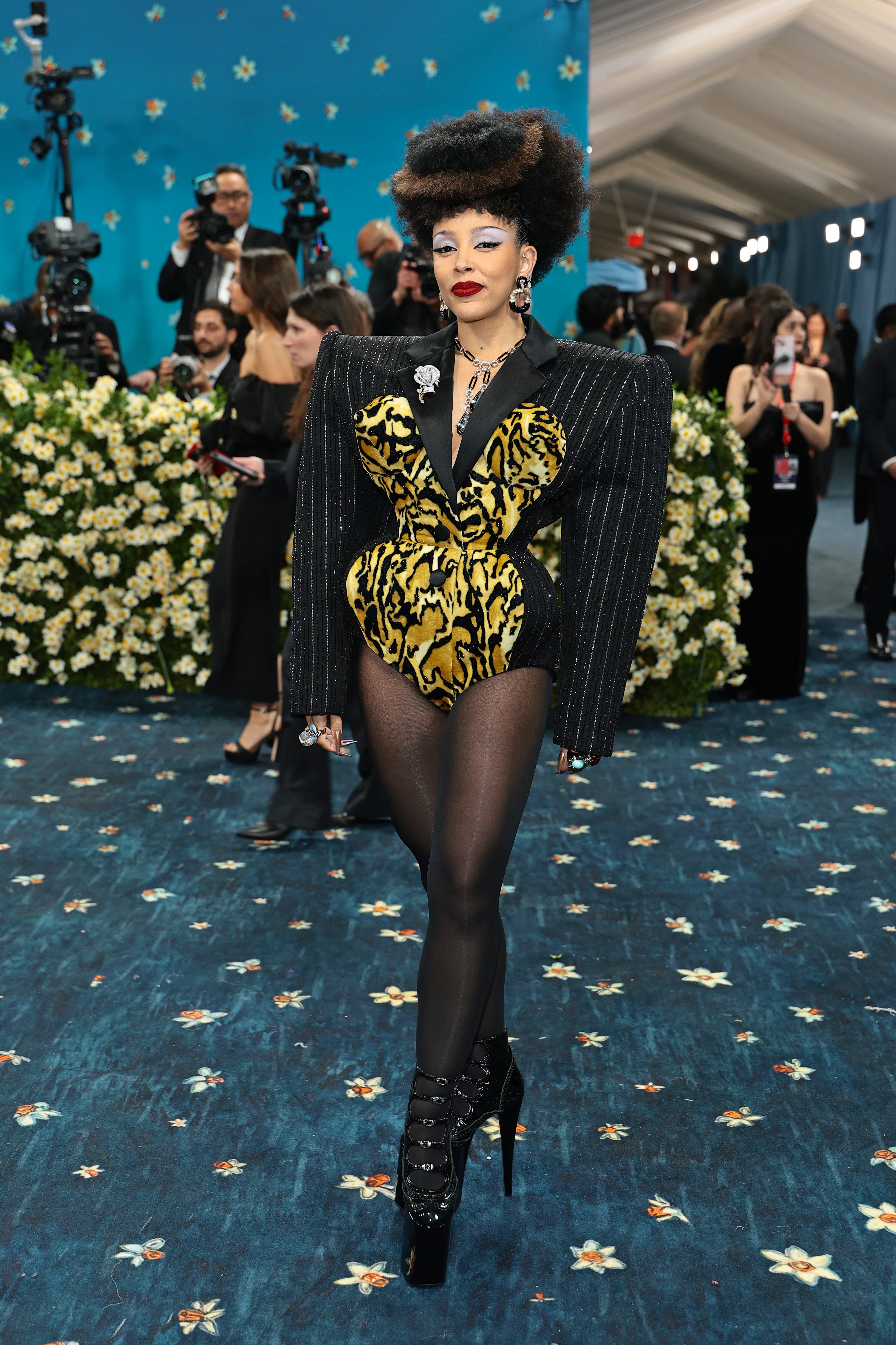 Doja Cat wore a custom pinstripe bodysuit with dramatic shoulder pads by Marc Jacobs. The long-sleeved outfit featured a cutout tiger print