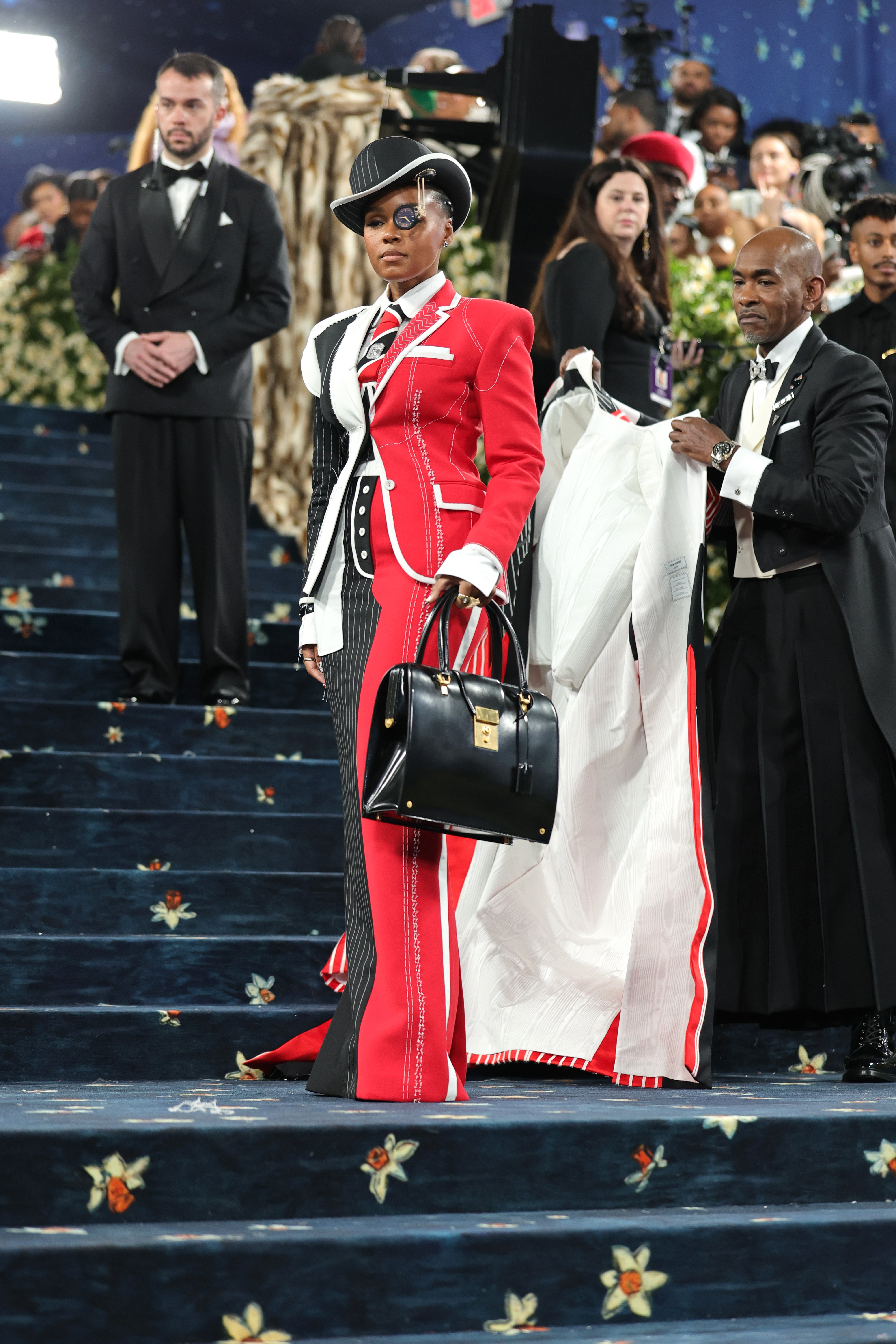 However, the singer then had their cover-up removed, revealing their full outfit: A suit that was half black and white, while the other half was red and white. They paired the look with a black purse and and black hat, which had a glass eye patch with a clock on it