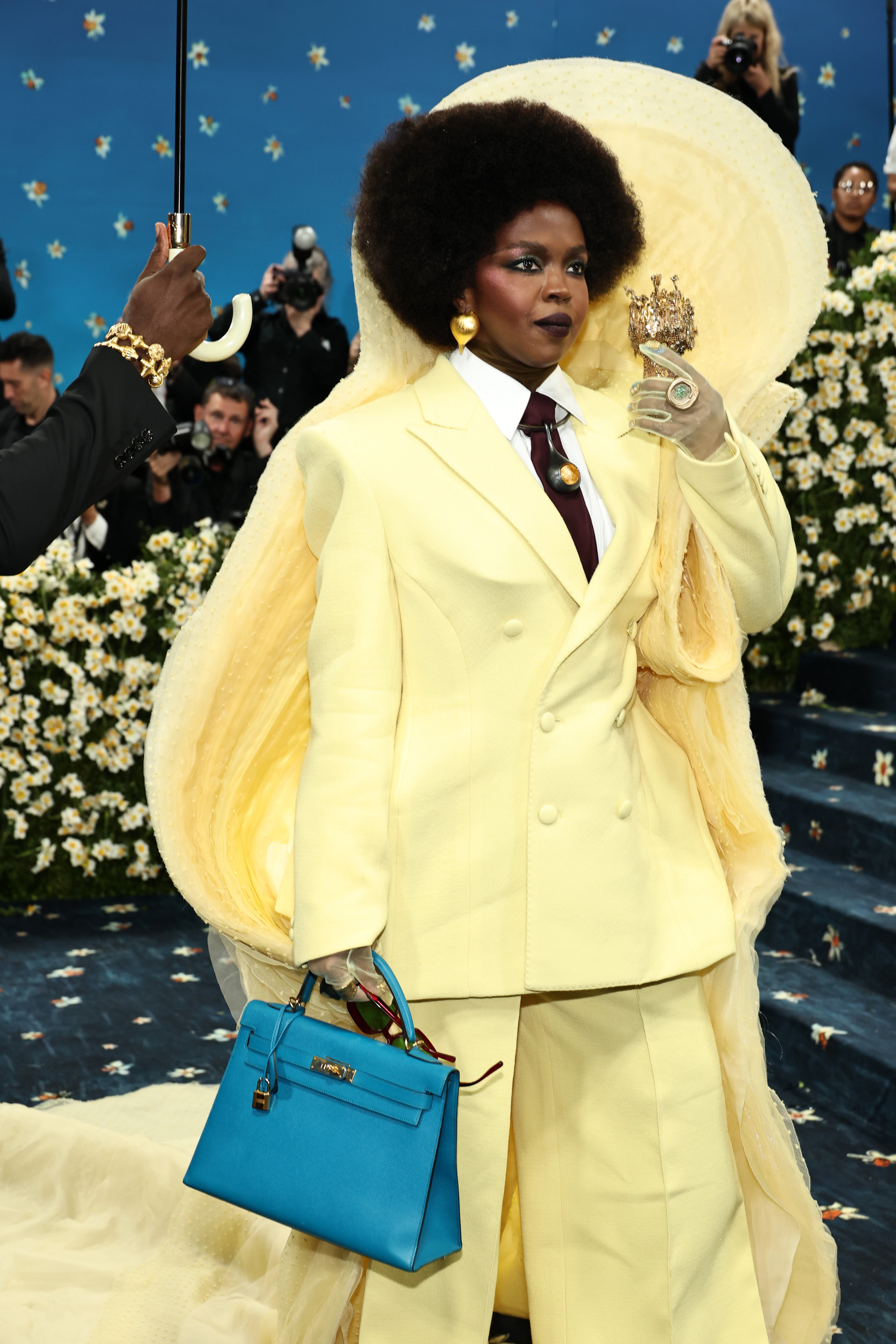 Lauryn Hill made her red carpet debut in a pale yellow tuxedo, paired with a white shirt and burgundy tie. Her suit featured a standout collar and long train. She also opted for gold earrings and rings